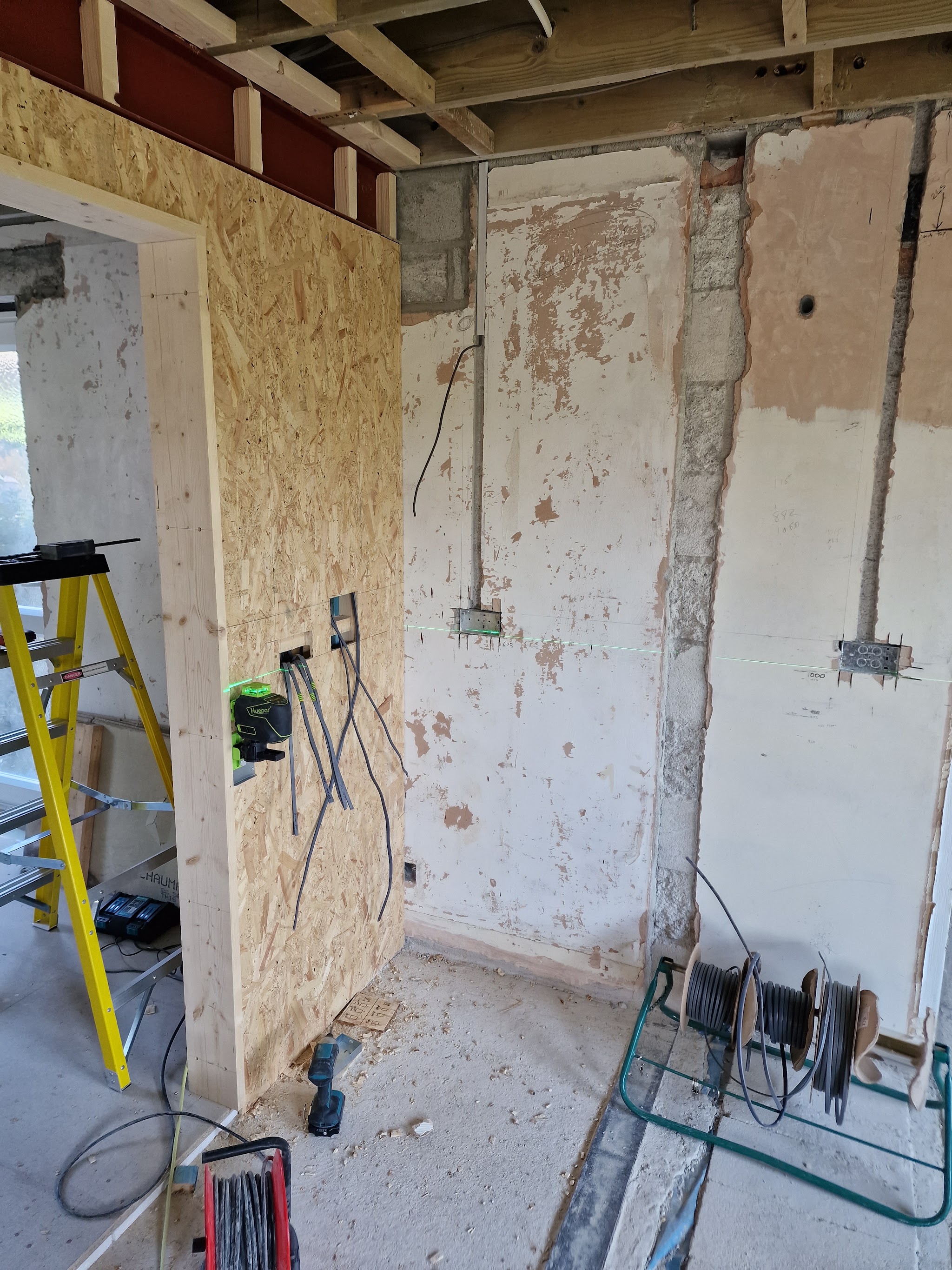 A stripped-back room at first fix, with new back boxes, chased walls and cable drums