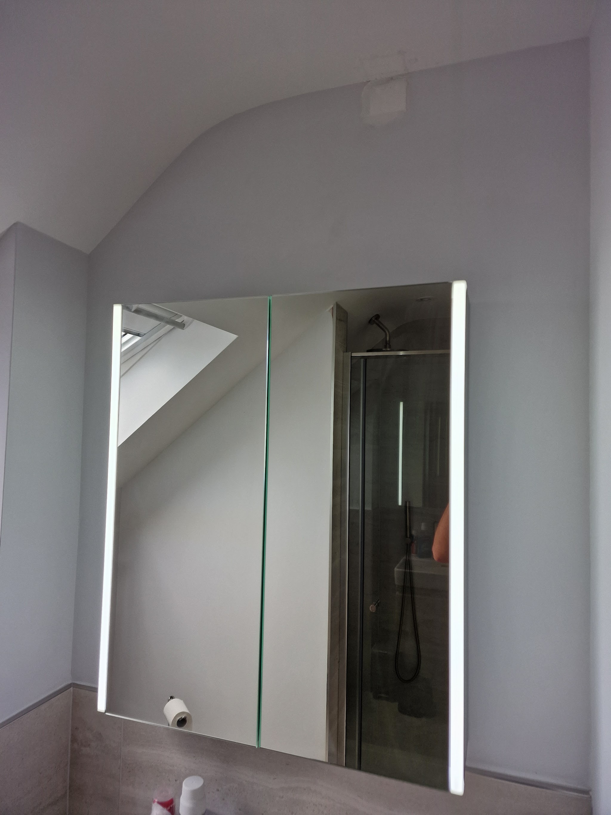 An illuminated mirror cabinet fitted in a bathroom